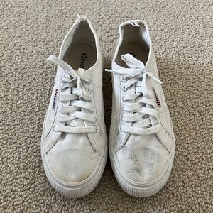 Heavily worn white supergas. In good condition with grey marks and tears.